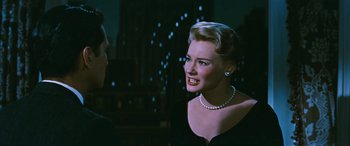Movie still from “The Best of Everything” (1959), directed by Jean Negulesco – A woman in a black dress talking to a man in a black suit; Close Up shot, Over the shoulder angle
