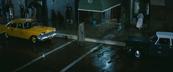 Movie still from “The Best of Everything” (1959), directed by Jean Negulesco – A man in a gray coat standing in the rain; Wide shot, High angle