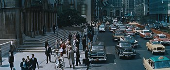 Movie still from “The Best of Everything” (1959), directed by Jean Negulesco – A group of people walking down a street next to cars; Extreme Wide shot, High angle