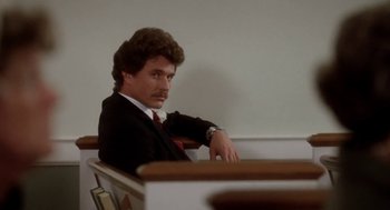 Movie still from “The Big Chill” (1983), directed by Lawrence Kasdan – A man sitting in a pew looking at the camera; Close Up shot, Low angle
