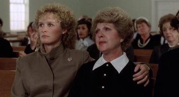 Movie still from “The Big Chill” (1983), directed by Lawrence Kasdan – Two women standing next to each other in front of a group of people; Close Up shot, High angle