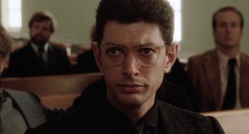 Movie still from “The Big Chill” (1983), directed by Lawrence Kasdan – A person wearing glasses and a suit; Close Up shot, Low angle