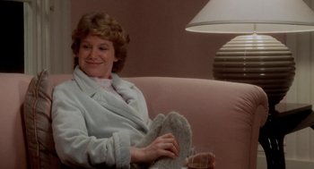 Movie still from “The Big Chill” (1983), directed by Lawrence Kasdan – A woman sitting on a couch with a glass of wine; Medium shot, Over the shoulder angle