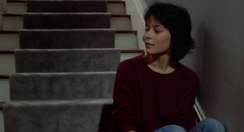 Movie still from “The Big Chill” (1983), directed by Lawrence Kasdan – A woman sitting on the steps of a staircase; Medium shot, High angle