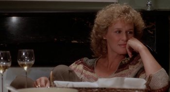 Movie still from “The Big Chill” (1983), directed by Lawrence Kasdan – A person sitting at a table; Close Up shot, Over the shoulder angle