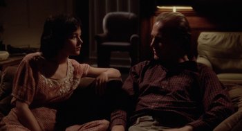 Movie still from “The Big Chill” (1983), directed by Lawrence Kasdan – A man and a woman sitting on a couch talking to each other; Medium shot, High angle
