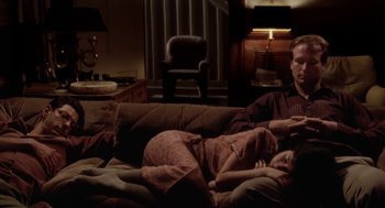 Movie still from “The Big Chill” (1983), directed by Lawrence Kasdan – A man and a woman laying on a couch in a living room; Medium shot, High angle