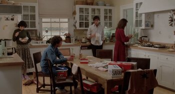 Movie still from “The Big Chill” (1983), directed by Lawrence Kasdan – A group of people standing around a table in a kitchen; Wide shot, High angle