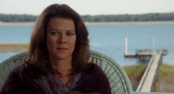 Movie still from “The Big Chill” (1983), directed by Lawrence Kasdan – A person sitting in a chair near a body of water; Close Up shot, Over the shoulder angle
