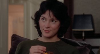 Movie still from “The Big Chill” (1983), directed by Lawrence Kasdan – A woman sitting on a couch holding a donut; Close Up shot, Over the shoulder angle