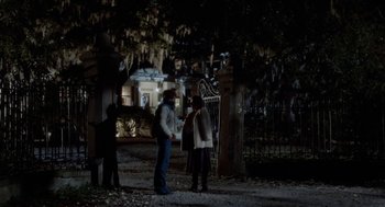 Movie still from “The Big Chill” (1983), directed by Lawrence Kasdan – Two people standing in front of a gate at night; Wide shot, Over the shoulder angle