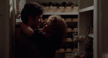 Movie still from “The Big Chill” (1983), directed by Lawrence Kasdan – A man and a woman hugging in front of a wine rack; Close Up shot, Low angle