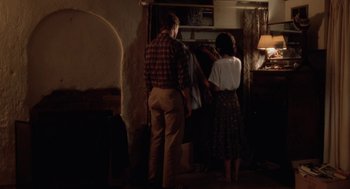 Movie still from “The Big Chill” (1983), directed by Lawrence Kasdan – A man and a woman standing in front of an open cabinet; Wide shot, Over the shoulder angle