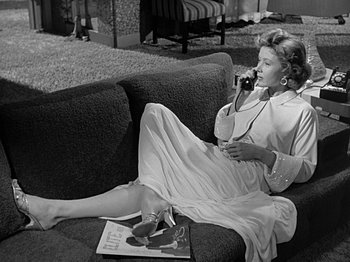 Movie still from “The Big Heat” (1953), directed by Fritz Lang – A woman sitting on a couch talking on the phone; Medium shot, High angle