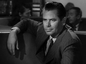 Movie still from “The Big Heat” (1953), directed by Fritz Lang – A man in a suit and tie sitting in a chair; Close Up shot, Over the shoulder angle