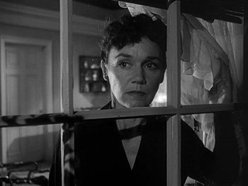 Movie still from “The Big Heat” (1953), directed by Fritz Lang – A black - and - white photo of a woman looking through a window; Close Up shot, Low angle