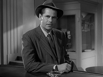 Movie still from “The Big Heat” (1953), directed by Fritz Lang – A black and white photo of a man wearing a suit and a hat; Medium shot, Low angle
