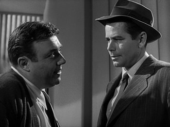 Movie still from “The Big Heat” (1953), directed by Fritz Lang – A man in a suit and a man in a hat talking to each other; Close Up shot, Over the shoulder angle