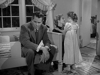 Movie still from “The Big Heat” (1953), directed by Fritz Lang – A man sitting on a bench next to two young girls; Medium shot, Over the shoulder angle