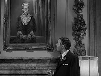 Movie still from “The Big Heat” (1953), directed by Fritz Lang – A black and white photo of a man in front of a painting; Medium shot, Over the shoulder angle