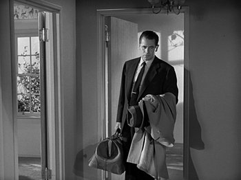 Movie still from “The Big Heat” (1953), directed by Fritz Lang – A black and white photo of a man in a suit holding a bag; Medium shot, Low angle