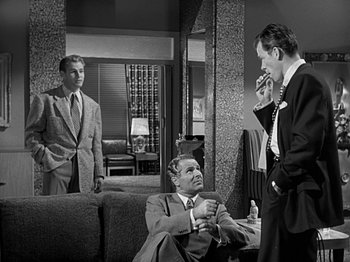 Movie still from “The Big Heat” (1953), directed by Fritz Lang – A group of men standing around a living room; Medium shot, Over the shoulder angle