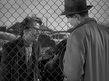 Movie still from “The Big Heat” (1953), directed by Fritz Lang – A man in a hat talking to a woman in a suit; Medium shot, Over the shoulder angle