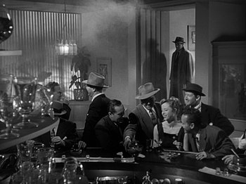 Movie still from “The Big Heat” (1953), directed by Fritz Lang – A group of people sitting at a table in a room; Wide shot, High angle
