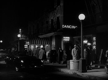 Movie still from “The Big Heat” (1953), directed by Fritz Lang – A black and white photo of people walking on the sidewalk; Wide shot, Low angle