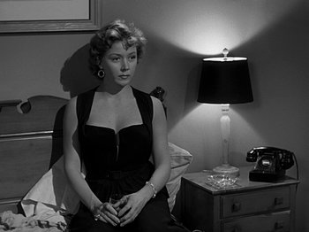 Movie still from “The Big Heat” (1953), directed by Fritz Lang – A black and white photo of a woman sitting on a bed; Medium shot, High angle