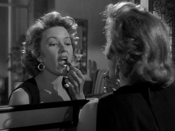 Movie still from “The Big Heat” (1953), directed by Fritz Lang – A black and white photo of a woman putting lipstick on; Close Up shot, Over the shoulder angle