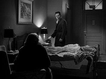 Movie still from “The Big Heat” (1953), directed by Fritz Lang – A black and white photo of a man and woman in a bedroom; Medium shot, Over the shoulder angle