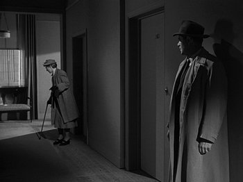 Movie still from “The Big Heat” (1953), directed by Fritz Lang – A man and a woman are standing in a hallway; Wide shot, High angle