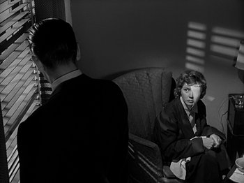 Movie still from “The Big Heat” (1953), directed by Fritz Lang – A man and a woman sitting on a couch in front of a window; Medium shot, Low angle