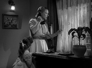 Movie still from “The Big Heat” (1953), directed by Fritz Lang – A woman and a little girl standing in front of a desk; Medium shot, Low angle