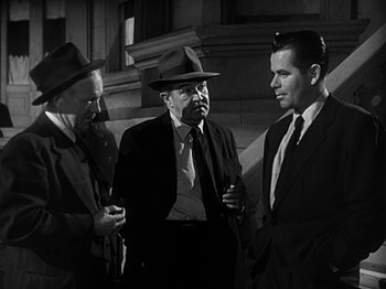 Movie still from “The Big Heat” (1953), directed by Fritz Lang – A group of men standing next to each other on a street; Medium shot, Over the shoulder angle