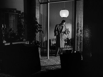 Movie still from “The Big Heat” (1953), directed by Fritz Lang – A man and a woman standing in front of an open door; Wide shot, Low angle