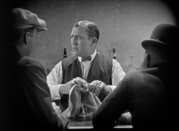 Movie still from “The Big Parade” (1925), directed by King Vidor – A man sitting at a table with two other men; Medium shot, Over the shoulder angle