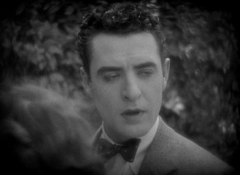 Movie still from “The Big Parade” (1925), directed by King Vidor – A black and white photo of a man in a suit and bow tie; Close Up shot, High angle