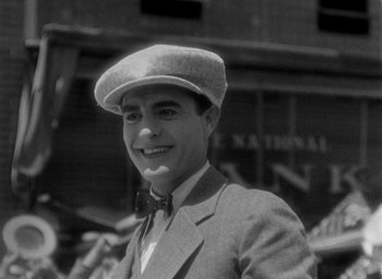 Movie still from “The Big Parade” (1925), directed by King Vidor – A man in a suit and hat smiling for the camera; Close Up shot, Low angle
