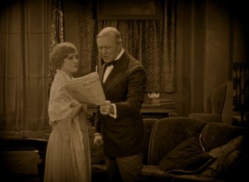 Movie still from “The Big Parade” (1925), directed by King Vidor – An older man and a young woman standing next to each other holding papers; Medium shot, High angle
