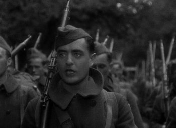 Movie still from “The Big Parade” (1925), directed by King Vidor – Black and white photograph of a man holding a rifle in front of a group of soldiers; Close Up shot, Low angle