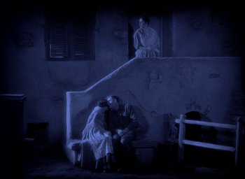 Movie still from “The Big Parade” (1925), directed by King Vidor – Two people sitting on a bench in a dark room; Wide shot, High angle