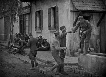 Movie still from “The Big Parade” (1925), directed by King Vidor – A black and white photo of a group of men standing around; Wide shot, High angle
