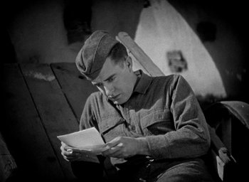Movie still from “The Big Parade” (1925), directed by King Vidor – A man sitting in a chair reading a book; Medium shot, High angle