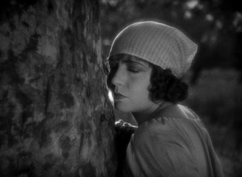 Movie still from “The Big Parade” (1925), directed by King Vidor – A woman leaning up against a tree with her eyes closed; Close Up shot, High angle