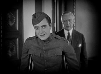 Movie still from “The Big Parade” (1925), directed by King Vidor – An old photo of a man and a man in a suit; Medium shot, High angle