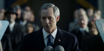 Movie still from “House of Cards” (2013), created by Beau Willimon – A person wearing a suit and tie; Close Up shot, Over the shoulder angle