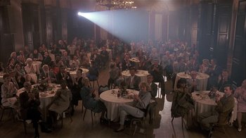 Movie still from “The Big Picture” (1989), directed by Christopher Guest – A group of people sitting at tables in front of a projector screen; Wide shot, High angle