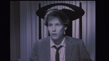 Movie still from “The Big Picture” (1989), directed by Christopher Guest – A man in a suit and tie sitting in a chair; Close Up shot, High angle